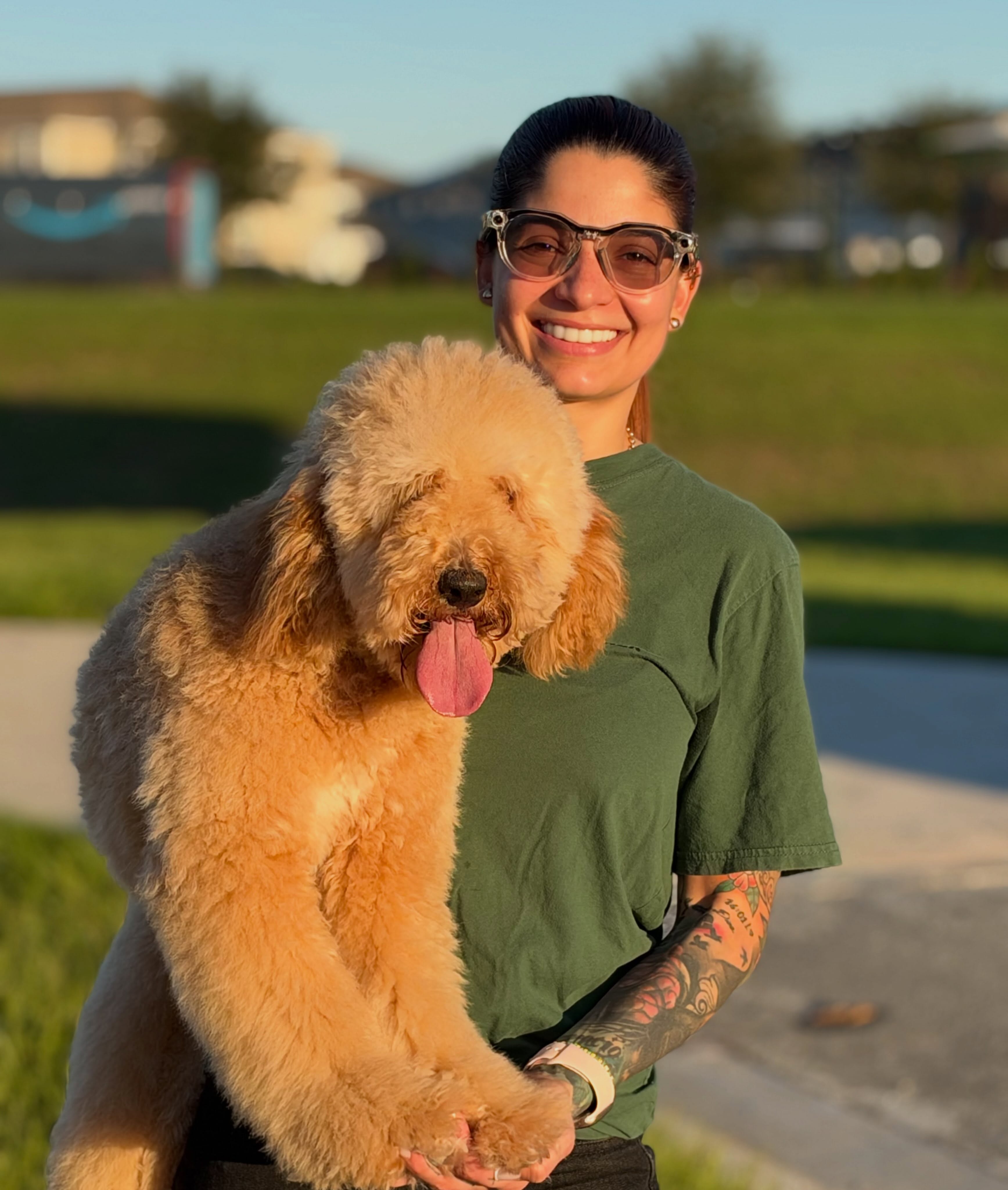 Entrenadora sonriendo con Arya, una poodle color crema