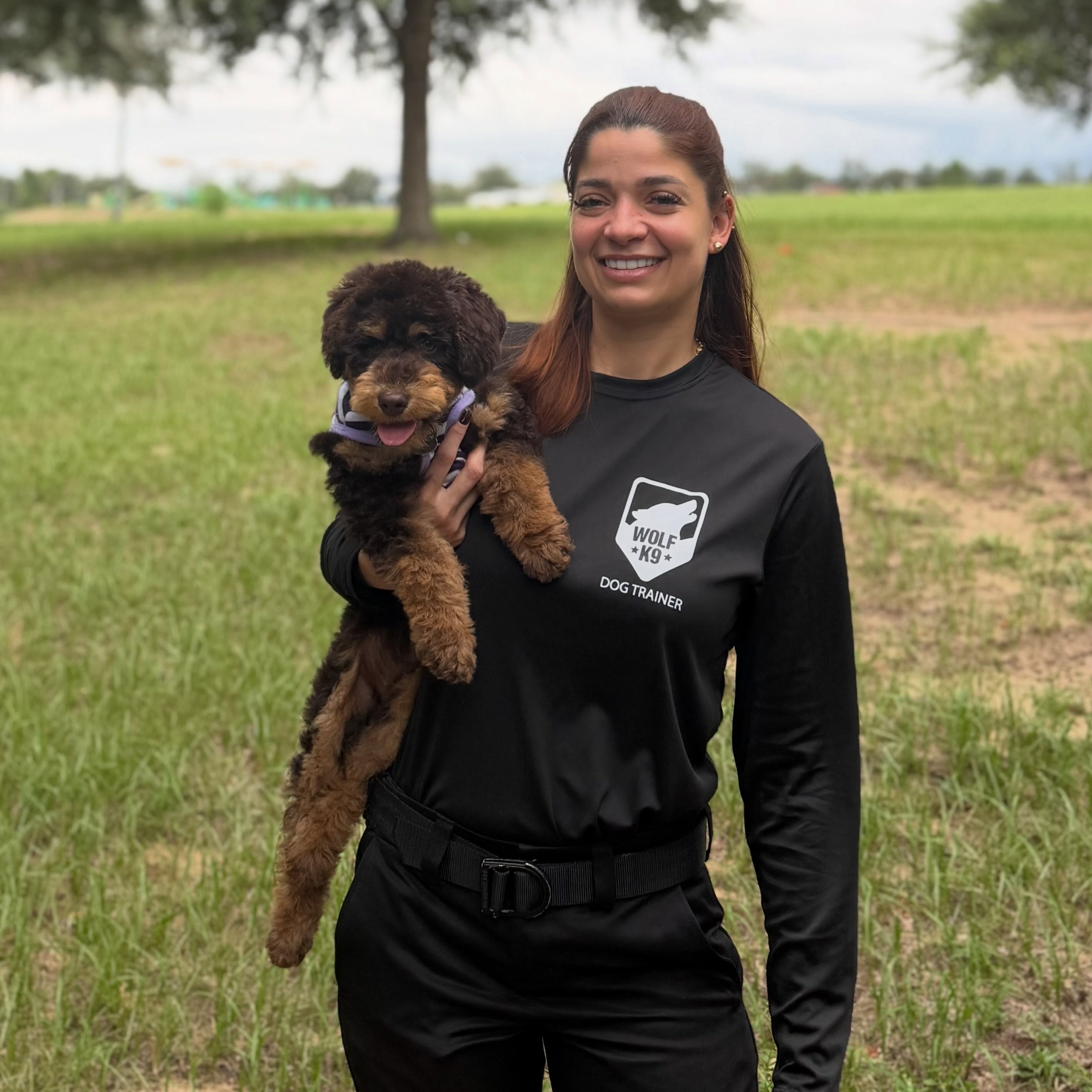 Johanna, adiestradora de Wolf K9 Training, con un cachorro poodle en brazos en Florida Central